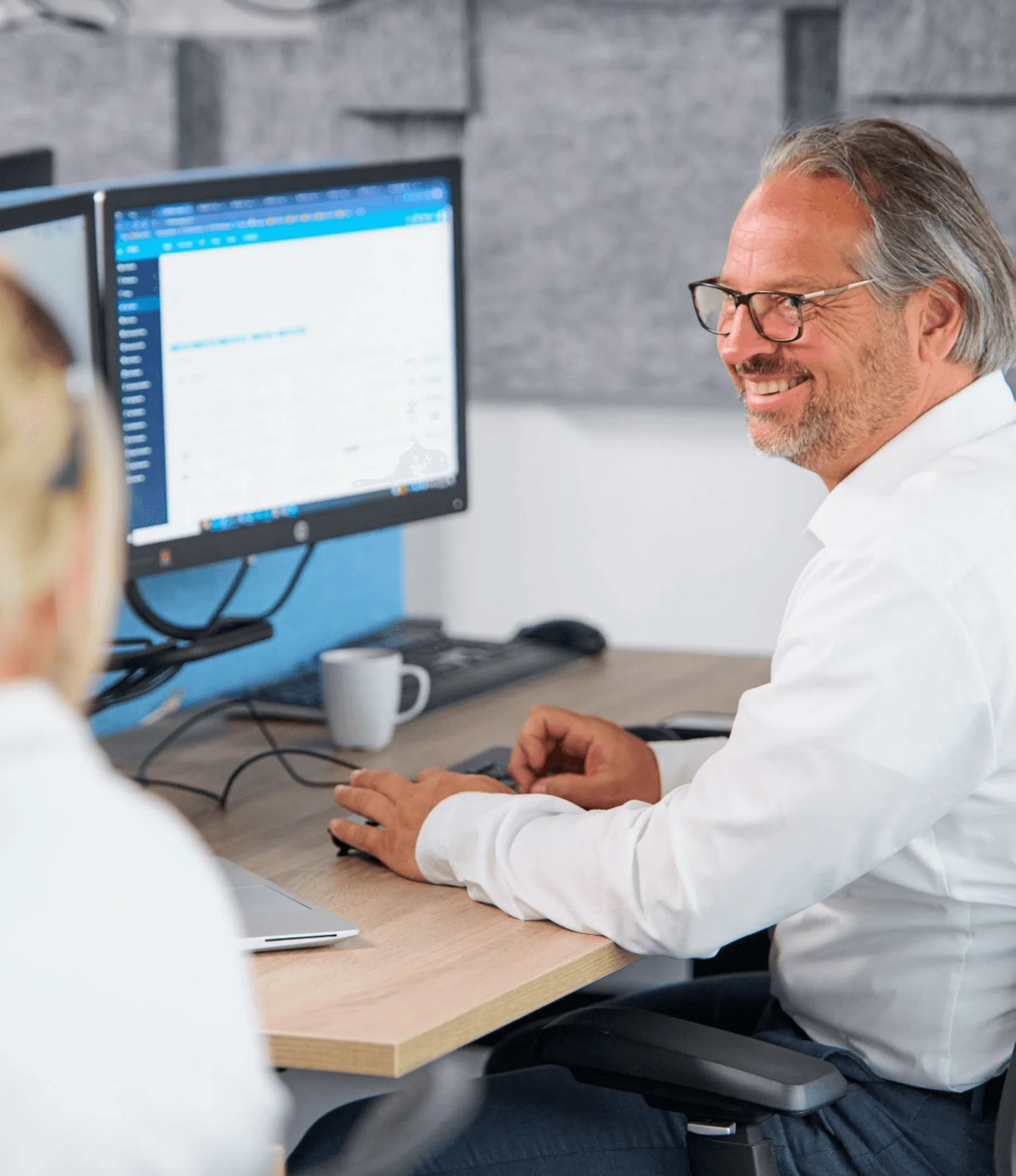 ICT-specialist van Westers in gesprek met een collega, achter zijn beeldscherm